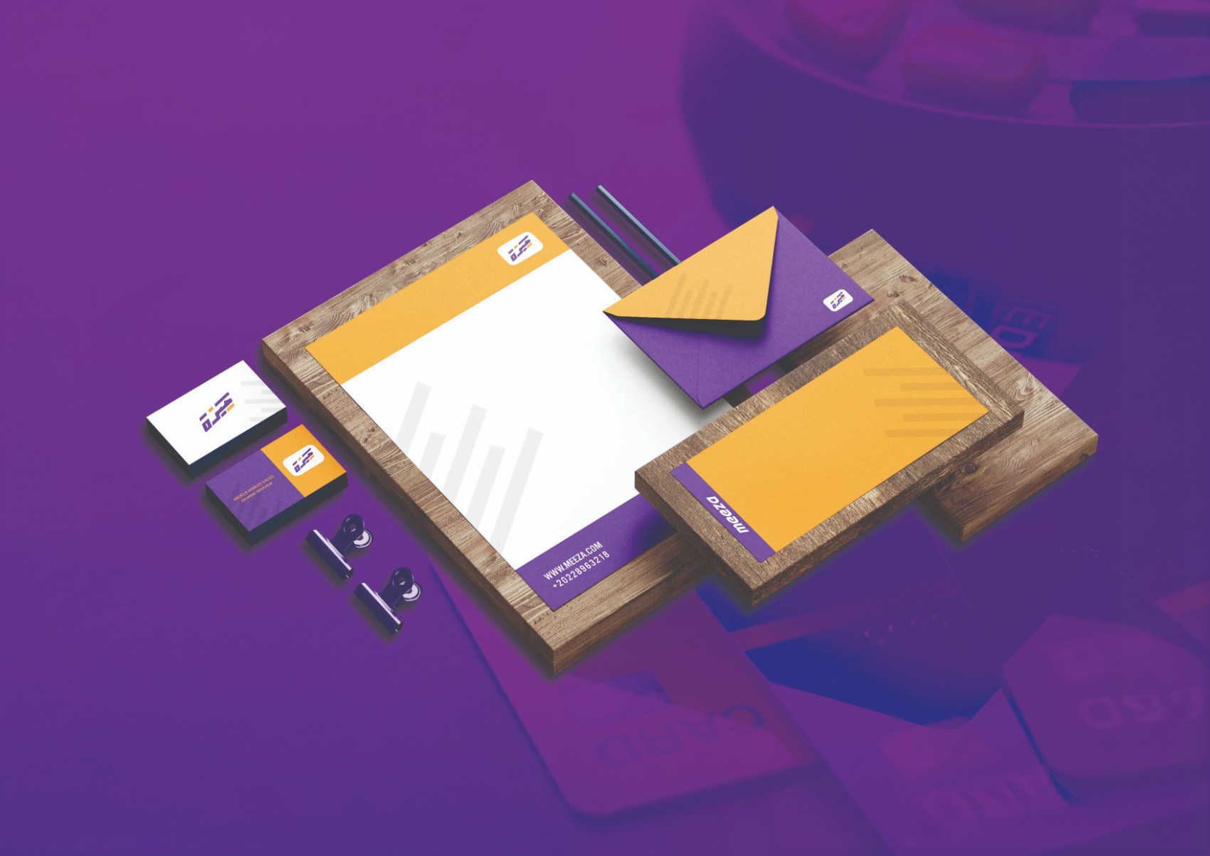 MEEZA stationery — letterhead, orange and purple envelopes, business cards on wooden boards